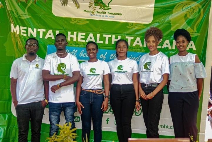 MHT team posing in front of a Mental Health Tanzania banner